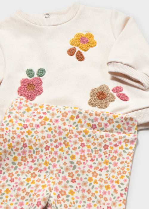 A cream-colored top with floral embroidery paired with multicolor floral print pants.