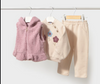 Beige sweatsuit with floral embroidered top and pink fur vest hanging on a rack.