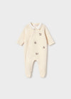 Cream velour footies with embroidered vintage toy motifs and snap button closure.