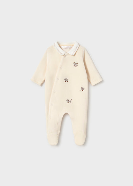 Cream velour footies with embroidered vintage toy motifs and snap button closure.