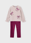 Light beige sweater with bow embellishments and raspberry velour leggings.