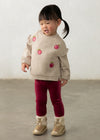 Toddler wearing a beige sweatshirt with raspberry embroidery and raspberry velour leggings.