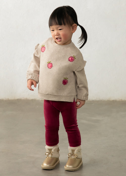 Toddler wearing a beige sweatshirt with raspberry embroidery and raspberry velour leggings.