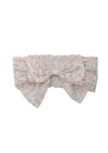 A soft pink headband with a large bow and delicate floral print.