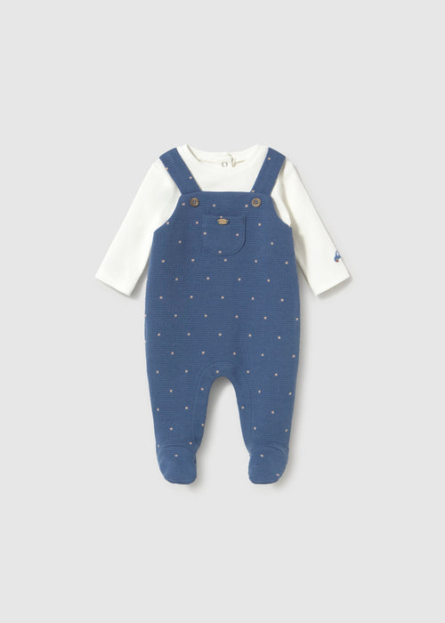 Navy footie with polka dots, designed to look like overalls, featuring long sleeves and foot coverage.