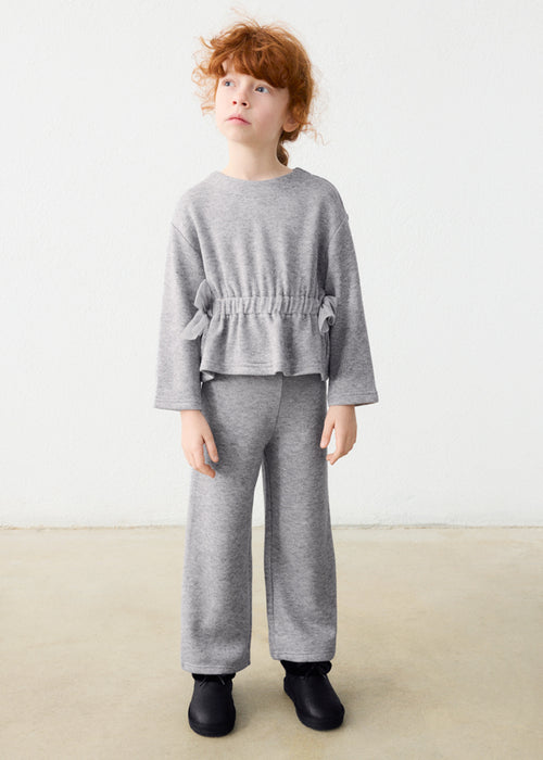 Girl wearing a grey shimmer 2-piece set with long sleeves and waist tie detail.