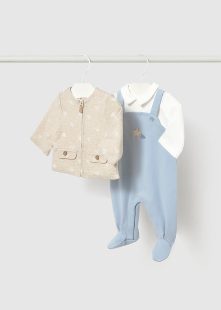 Blue footie overall with a star motif and a beige jacket on a hanger.